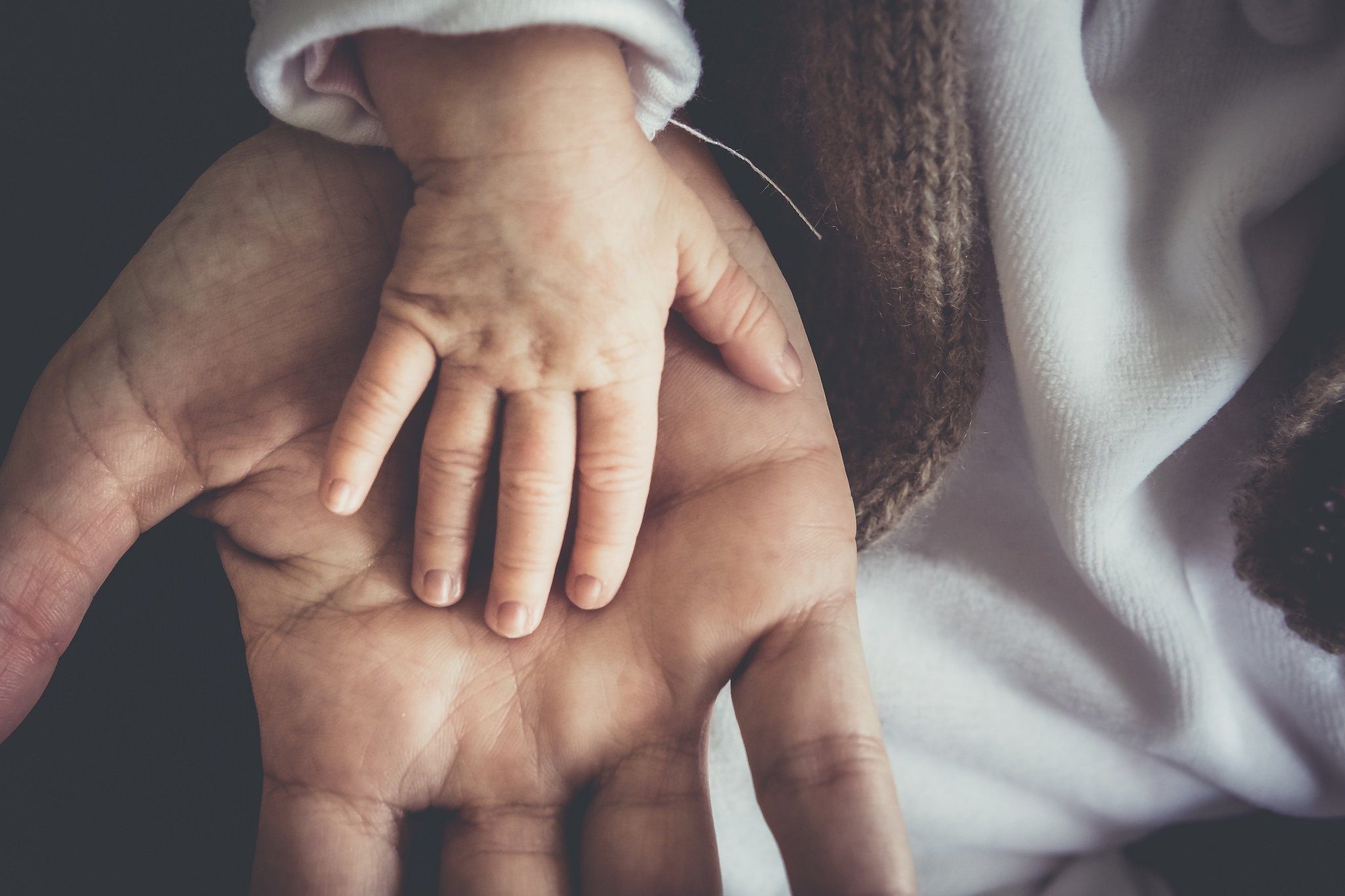 Mano de bebé encima de mano de adulto